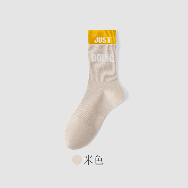 A single ribbed ankle sock in a light beige/cream color with a bright yellow cuff. T